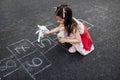 Above view image of little girl playing with the toy sheep on hopscotch on playground. Child playing the game outside. Kid playing