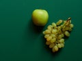 Isolated set of a green apples with a bunch of sweet seedless grapes in studio with green background