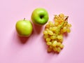 Isolated set of a green apples with a bunch of sweet seedless grapes in studio with millennial pink background Royalty Free Stock Photo