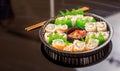 Above view of large set of delicious japanese rolls on a black plastic plate over a wooden table