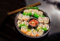 Above view of large set of delicious japanese rolls on a black plastic plate over a wooden table