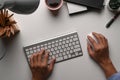 Above view of man hand typing on keyboard and holding mouse on white desk