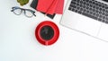 Above view of modern workspace with laptop, coffee cup, notebook and glasses on white table. Royalty Free Stock Photo