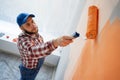 above view of painter painting a wall with paint roller. Orange color in decoration Royalty Free Stock Photo