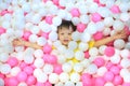 Above view portrait of cute little Asian kid in ball pit full of colorful plastic balls smiling at camera while having fun in Royalty Free Stock Photo