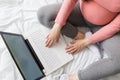 Above view of pregnant woman working on laptop while sitting on bed at home Royalty Free Stock Photo