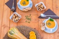 Above view of a raw pumpkin on the wooden table with bread croutons and two bowls of delicious and healthy pumpkin cream