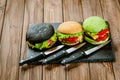 From above view of set of three color homemade burgers with marble beef with knifes wooden table Royalty Free Stock Photo