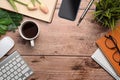 Simple workspace with coffee cup, smart pone, notebook and houseplant on wooden desk.