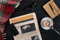 Above view of Smart phone, newspaper, scarf in a cage, glasses with notebook and cup of latte coffee on black wooden Royalty Free Stock Photo