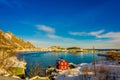 Above view of some wooden buildings in the bay with boats in the shore in Lofoten Islands surrounded with snowy