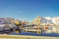 Above view of some wooden buildings in the bay with boats in the shore in Lofoten Islands surrounded with snowy
