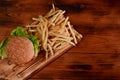 Tasty fish burger.and fried potatoes on wooden table. Royalty Free Stock Photo