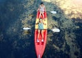 Above view of two smiling friends kayaking on the ocean together over summer break. Portrait of happy women canoeing and