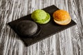 From above view of variety of three hamburger buns on wooden table. Black, green, yellow buns