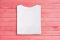 Above view of white folded blank t-shirt on pink wooden background. Female tshirt design template Royalty Free Stock Photo