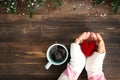 Above view of woman hand holding red heart with hot cup of coffee on wood table. Royalty Free Stock Photo