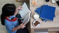 Above view of young girl reading book while sitting on floor in living room. Royalty Free Stock Photo