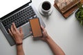 Young woman working on laptop computer and holding smart phone at her office desk. Royalty Free Stock Photo