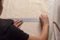 An unrecognizable seamstress is measuring fabric using a rule