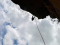 Abseiling a negative sanstone rock wall with blue sky on background