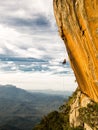 Abseiling a negative yellow rock wall with mountains on background