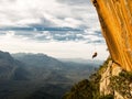 Abseiling a negative yellow rock wall with mountains on backgrou after rock climbing