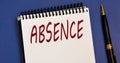 ABSENCE - word in a white notebook on a blue background with a pen Royalty Free Stock Photo