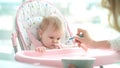 Absently baby not eating puree. Mother feeding daughter. Infant eating dinner Royalty Free Stock Photo