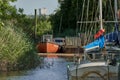 Vintage orange boat with funny name `auf ein neues` is lying in a hidden corner of the marina