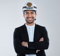 Absolute power corrupts absolutely. a young business man wearing a mining hat against a grey background.