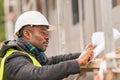 African engineer checking office blueprints on construction site Royalty Free Stock Photo