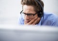 Absorbed in his work. A handsome young businessman wearing a headset while concentrating on his computer screen. Royalty Free Stock Photo