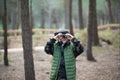 Absorbed little boy with binoculars in forest