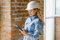 Absorbed in the work of a woman engineer working with a tablet on the background of the construction site. Portrait of a Royalty Free Stock Photo