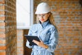 Absorbed in the work of a woman engineer working with a tablet on the background of the construction site. Portrait of a Royalty Free Stock Photo