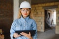 Absorbed in the work of a woman engineer working with a tablet on the background of the construction site. Portrait of a Royalty Free Stock Photo