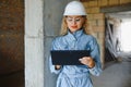 Absorbed in the work of a woman engineer working with a tablet on the background of the construction site. Portrait of a Royalty Free Stock Photo