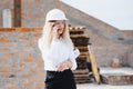 Absorbed in the work of a woman engineer working with a tablet on the background of the construction site. Portrait of a Royalty Free Stock Photo