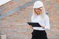 Absorbed in the work of a woman engineer working with a tablet on the background of the construction site. Portrait of a Royalty Free Stock Photo