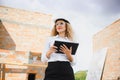 Absorbed in the work of a woman engineer working with a tablet on the background of the construction site. Portrait of a Royalty Free Stock Photo