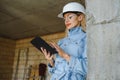 Absorbed in the work of a woman engineer working with a tablet on the background of the construction site. Portrait of a Royalty Free Stock Photo