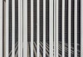 Abstract architectural pattern of white vertical louvers and industrial metal grating. Royalty Free Stock Photo
