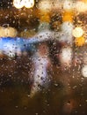 Abstract background autumn rain in the night city, silhouette of a young woman with an umbrella behind a wet window Royalty Free Stock Photo
