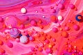 Abstract background of bobbly and mixed red, orange, white, and pink oily paints