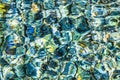 Abstract background of clear sea or river water ripple waves in blue, green, yellow color. Sea water with different color pebbles Royalty Free Stock Photo