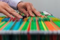 Abstract background colorful hanging file folders in drawer. Male hands looking document in a whole pile of full papers