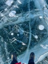 The natural texture of winter ice with white bubbles and cracks on a frozen lake. Abstract background of ice and cracks on the