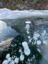 The natural texture of winter ice with white bubbles and cracks on a frozen lake. Abstract background of ice and cracks on the Royalty Free Stock Photo