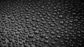 Many drops of water on a dark surface - non-stick coating in a pan. Center in sharpness, blurred edges. Black